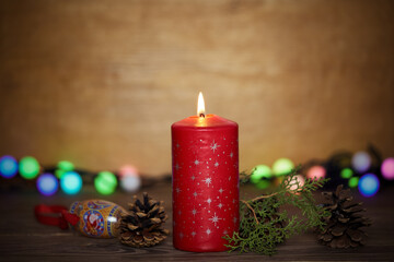 Lighted candle on the background of New Year's glowing multi-colored garlands