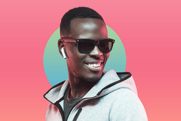 Portrait of young african athlete listening music with earphones, wearing sunglasses isolated on...