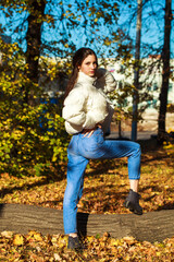 Young beautiful brunette girl in blue jeans, autumn park outdoor