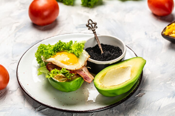 Trendy Raw Vegan avocado burger with fesh vegetables and bacon, egg, Ketogenic diet breakfast. Keto, paleo lunch, Copy space for text