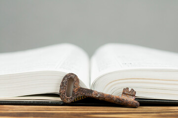 Open book Bible. Old rusty key. Knowledge discovery concept.