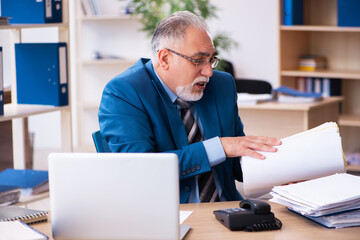 Old male bookkeeper unhappy with excessive work at workplace