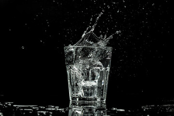 Water in glass isolated on black background. Splashes and drops of water. banner, catering menu recipe place for text,