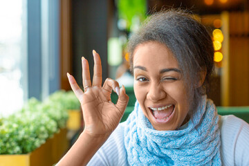 Portrait of an African American woman with a video call. She showing allright gesture.