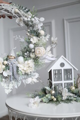 Cristmass decoration  with deoll and pine on hands  and house on table