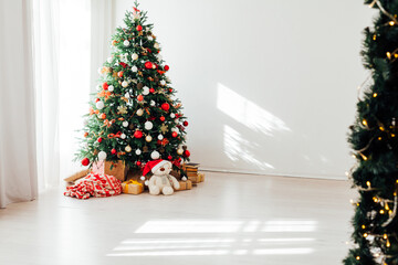 Christmas tree with gifts of garland lights for the new year in the interior of the white room as a backdrop