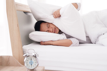 Asian man wake up and alarm clock sounds so loud and noisy. He is  lazy to go to work in the...