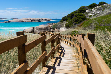 Wooden pathway leading down to a beach with bright turquoise sea