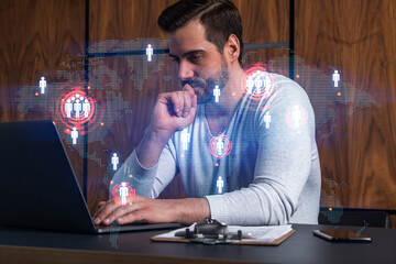 A serious caucasian manager in casual wears, using laptop to develop a new worldwide supply chain. Double exposure. globe and map hologram.