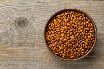 Dried red beans in a clay bowl on a wooden table. Space fot text.