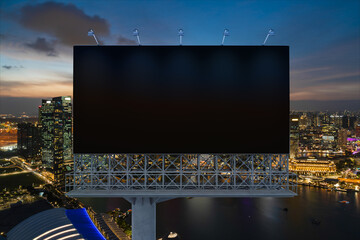 Blank black road billboard with Singapore cityscape background at night time. Street advertising poster, mock up, 3D rendering. Front view. The concept of marketing communication to sell idea.