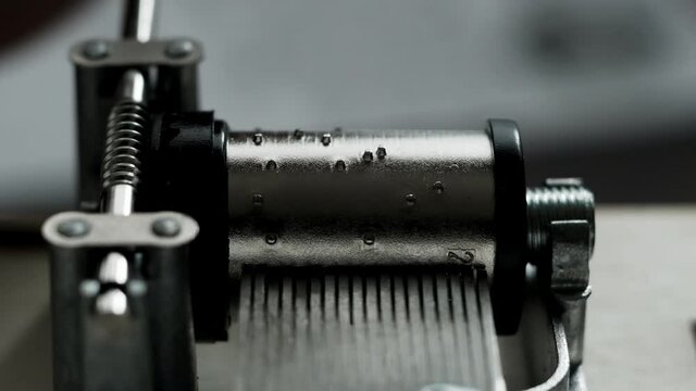 Music box mechanism rotates close-up on white background. Insides of music box during work. worm-gear.
