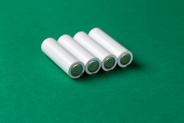 Rechargeable AAA batteries in white on a green background. Place for text.