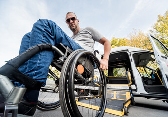 A man in a wheelchair on a lift of a vehicle for people with disabilities