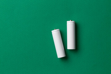 Rechargeable AAA batteries in white on a green background. Place for text.