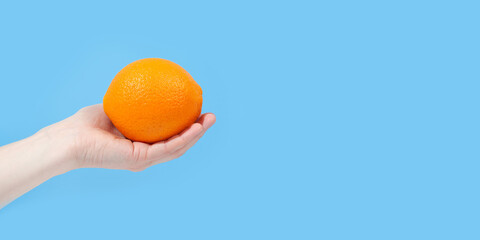 Hand holding organic delicious orange Isolated on blue Background. Healthy eating and dieting concept. Copy space. Free space for your text