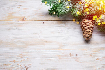 Snowy fir branch with fir cones on wooden table. Christmas or New Year holiday background.