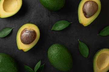 Avocado pattern on black stone background. Flat lay. Horizontal orientation.