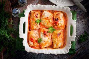 Cabbage rolls with minced meat and rice baked in the oven on the table in a ceramic form, top view