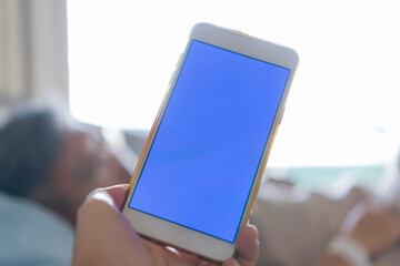Hospital Patients woman senior using smart phone, Blue Screen Mock up smartphone for Text with another patient on hospital bed for Telemedicine Care advice, Health care technology concept