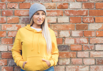 Happy girl looks to side. Young smiling woman model posing against bricks wall