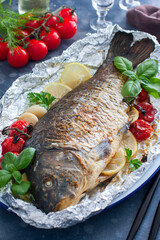 whole baked carp in foil with lemon in the oven, selective focus