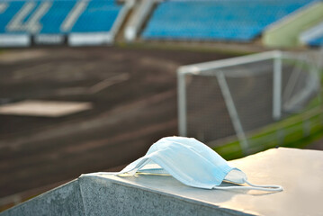 Blue protective mask on the background of chairs. The mask was left by the fan at the stadium. The concept of prohibition during a coronavirus pandemic.