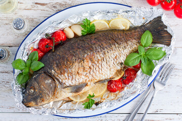 whole baked carp in foil with lemon in the oven, top view, horizontal