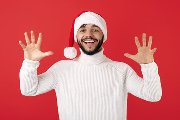 Cheerful hipster man wears santa claus hat celebrate success over red background. Christmas and New Year concept.