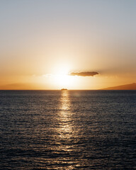 A sunset over the sea with a cruise ship in the middle of it
