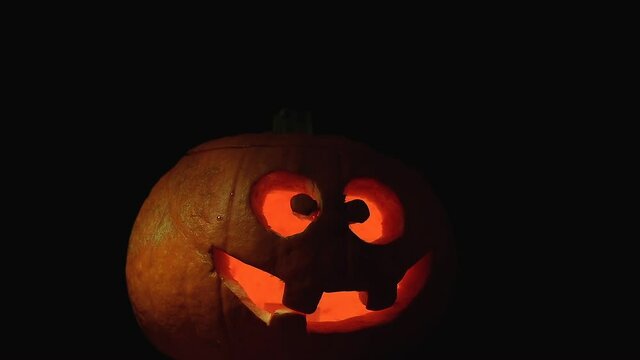 appearance of an orange pumpkin with scary smile. Halloween concept and horror scene on black background