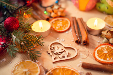 Self made wooden christmas tree decoration on wooden table with burning candles, sticks of cinnamon, dried slices of orange and branches of fir-tree. Festive atmosphere