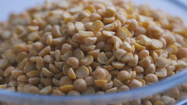 Dry split peas close-up. Macro video of the falling peas. 4K video. Organic legumes.