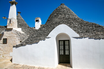 Fototapeta na wymiar Trulli houses in Alberobello village, Italy. A trullo house is a traditional apulian dry stone hut with a conical roof.