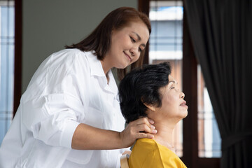 Obraz na płótnie Canvas Asian caregiver massaging retired senior woman, concept of retirement, old age home, senior home, pensioner service, caretaker business