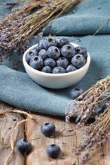 Juicy blueberries with sprigs of lavender on a wooden background.