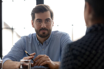 Meeting one on one. Attentive man customer listening to broker or consultant before taking out insurance policy sign up a contract purchase service, confident male hr thinking of hiring job candidate