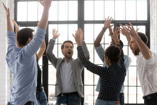 We are the best. Active inspired diverse millennial young business partners staff members teammates colleagues meeting on motivation training raising hands up shouting screaming corporate motto slogan