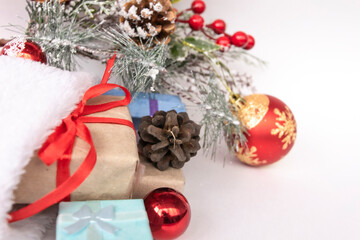 Beautiful Christmas composition with gift box tied with a ribbon, presents, Santa hat and fir branches on white background.