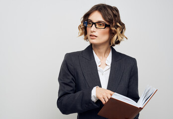 Business woman with a book in her hands on a light background classic suit fashionable hairstyle Copy Space