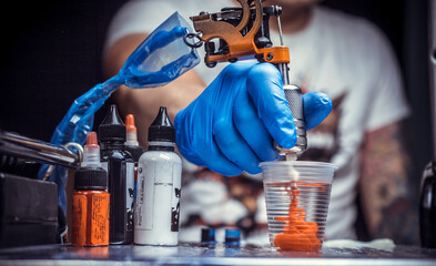Hand of a tattoo artist, holding a tattoo machine.