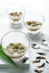 A view of no sauce glutinous rice ball or Putri Mandi in glass bowl as Indonesian dessert. Selective focus in shiny background