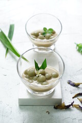 Shiny background for Kolak Putri Mandi or glutinous rice ball compote with pandan leaves, dried butterfly pea flowers and some mints. Selective focus
