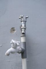 Silver and white air tap in gray broken wall background along with pipe