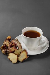 A white cup of ginger tea in dark grey background