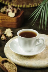Focus on a white cup of ginger tea in dark grey background