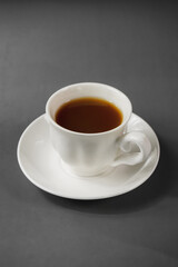 Focus on a white cup of ginger tea in dark grey background