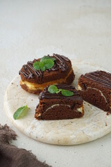 A view of slices heavenly chocolate cheese cake with mint leaves for garnish in marble board and grainy texture background  