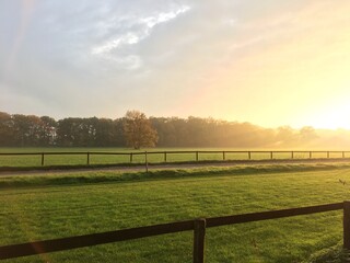 Faszinierendes Licht während des Sonnenuntergangs über einer herbstlichen Landschaft mit Wiese...