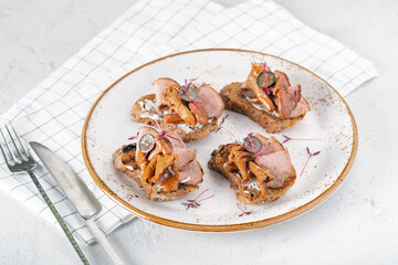 Smorrebrod, a traditional Scandinavian open sandwich with chanterelle mushrooms and ham on white plate